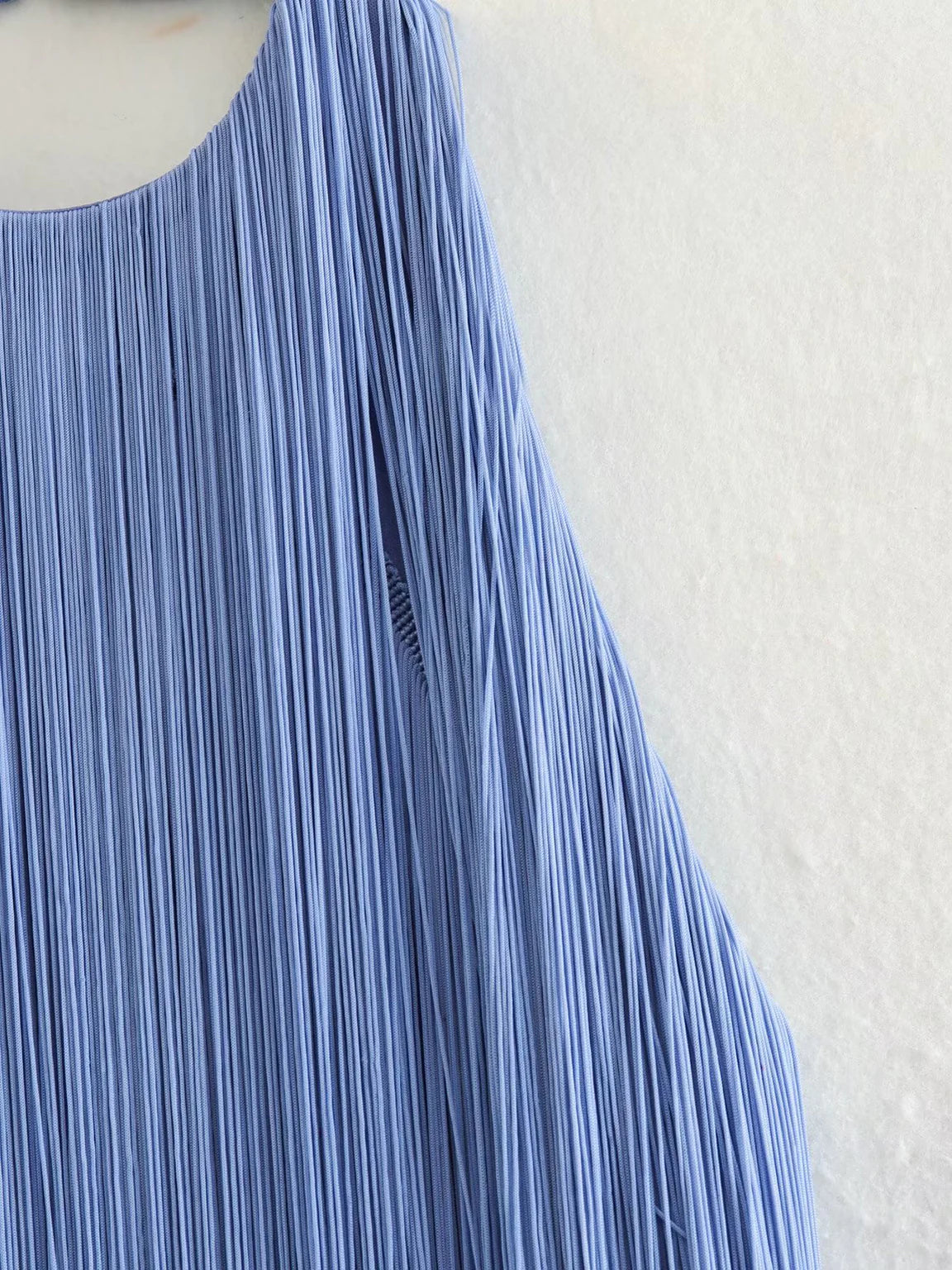 Close-up of a pleated blue dress on a textured white background. #Addtl