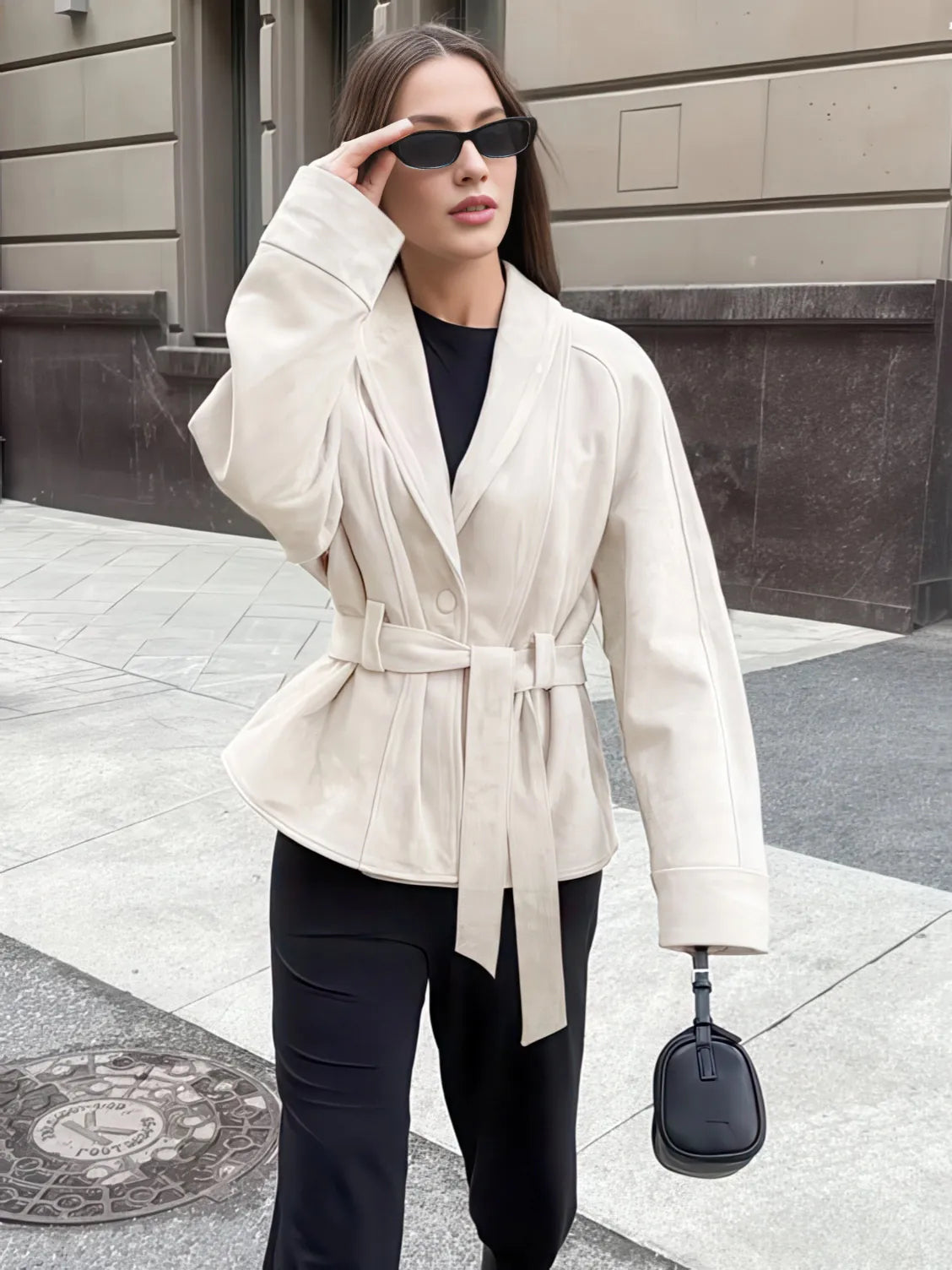 Woman wearing a beige trench coat and black pants on a city street. #Color_Beige