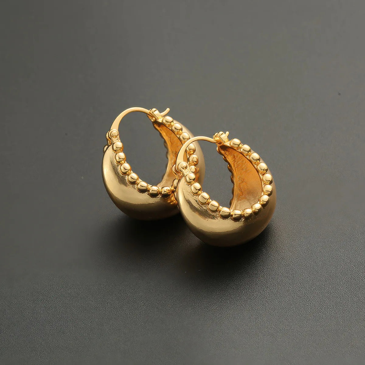 Gold hoop earrings on a dark gray background. #Style_C