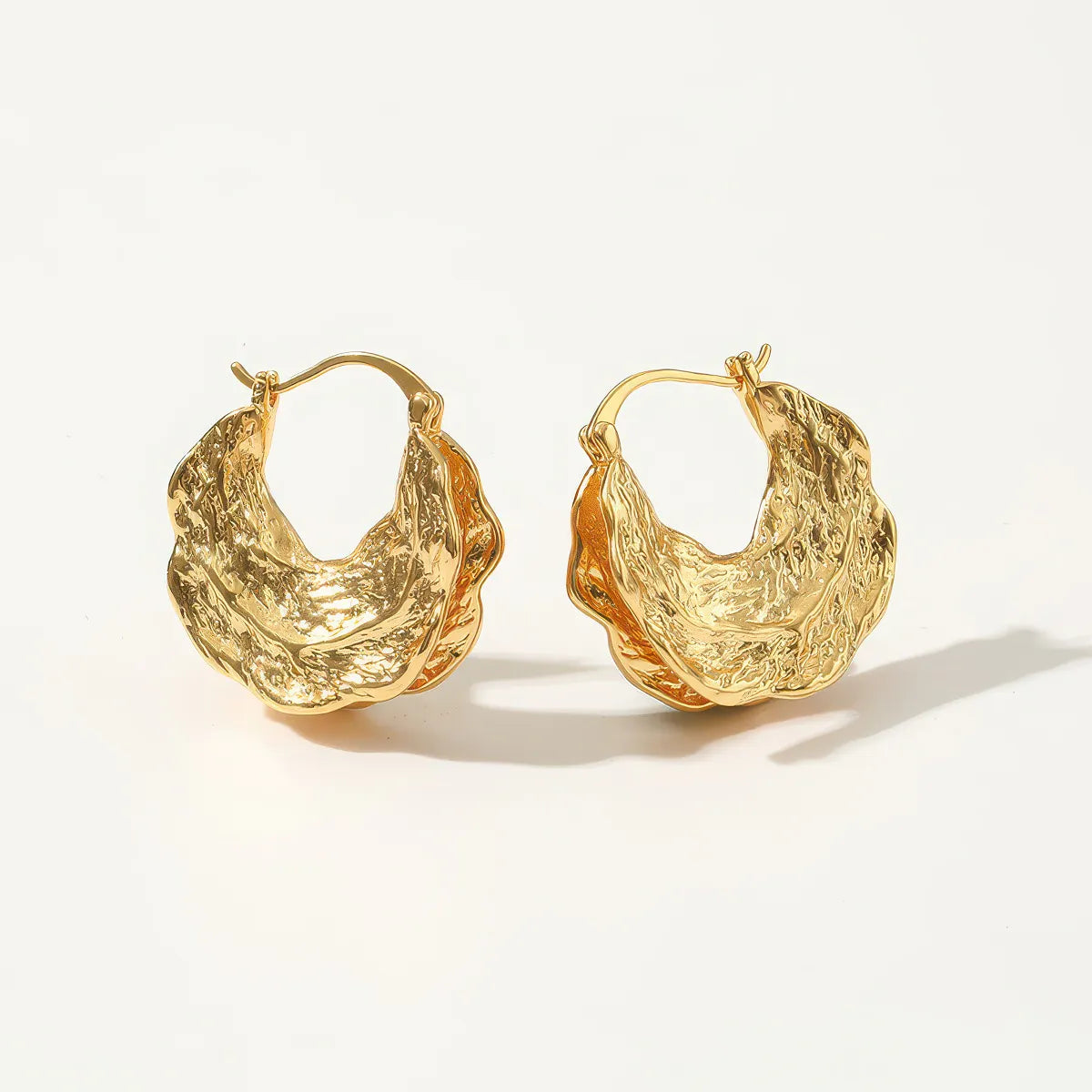 Pair of gold hoop earrings on a light background. #Style_D