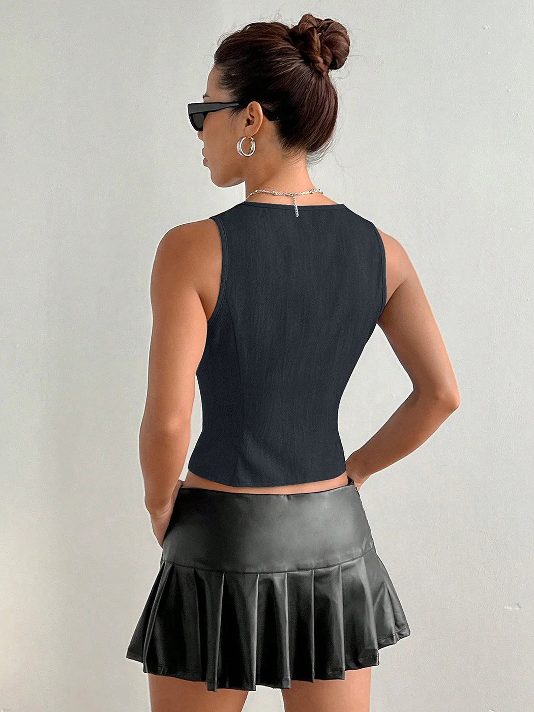 Woman wearing a black sleeveless top and pleated skirt against a plain background #Color_MidnightBlue