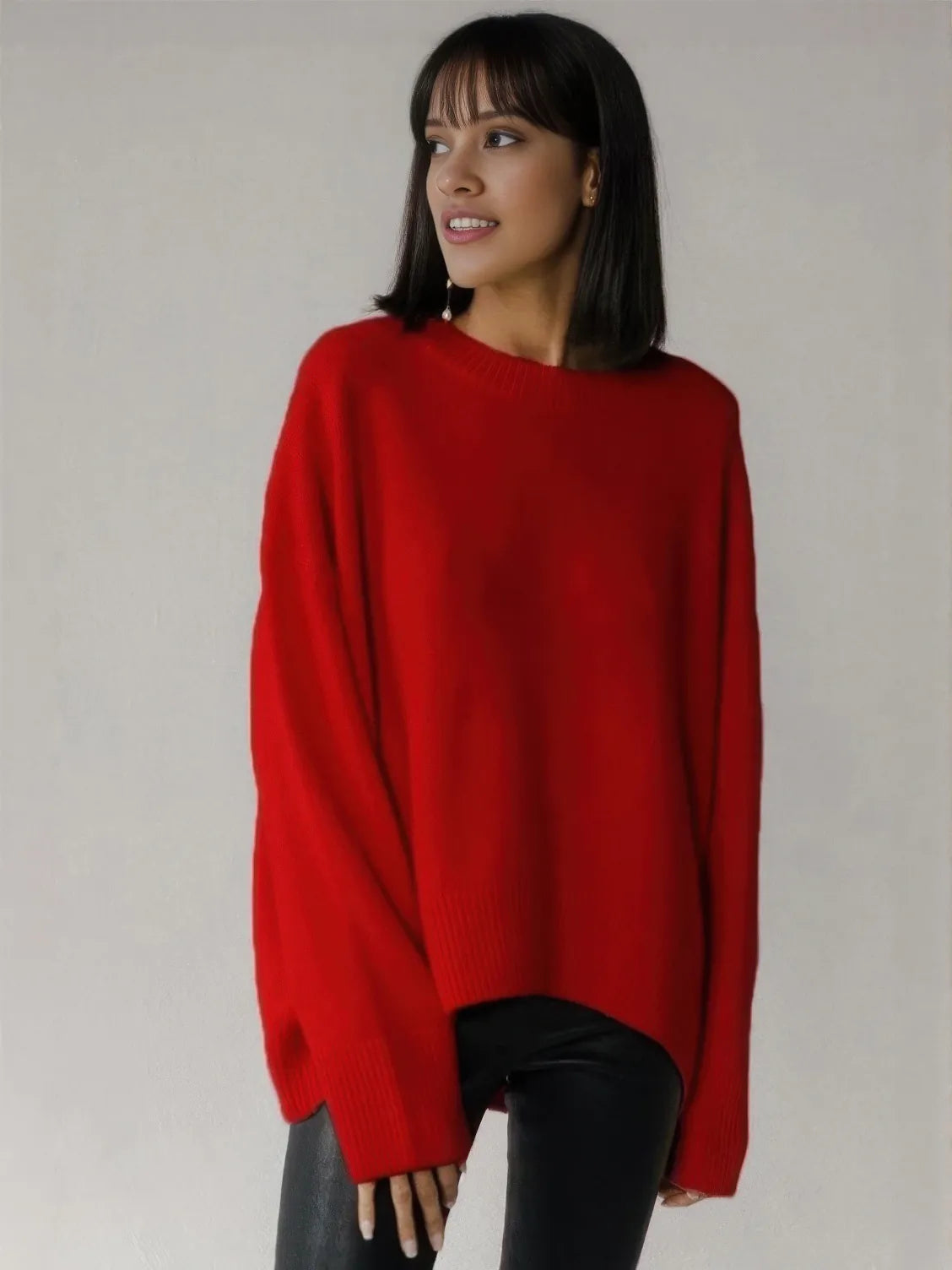 Woman wearing a red sweater against a plain background. #Color_Red