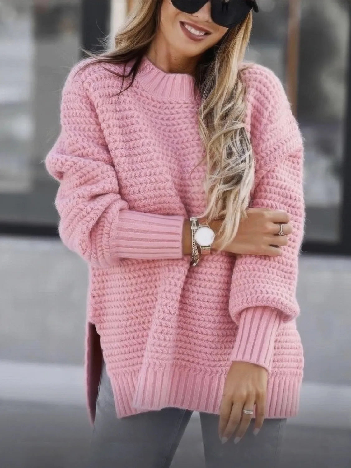 Woman wearing a pink knitted sweater with a blurred background. #Color_Pink