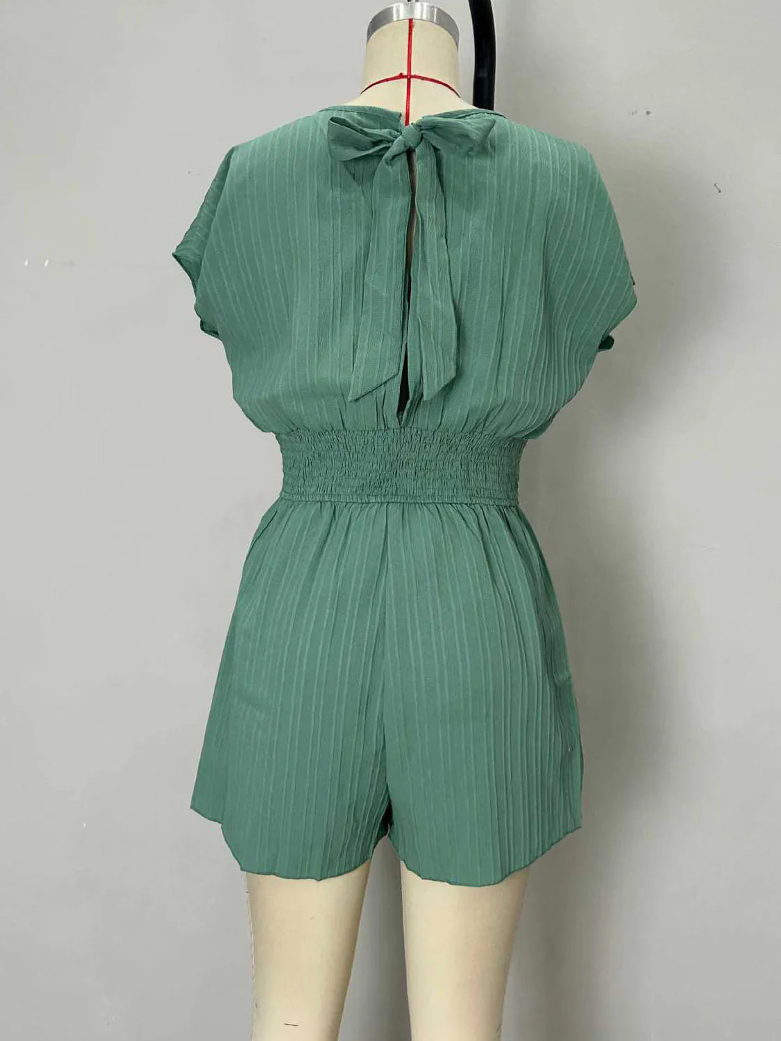 Green romper on a mannequin against a gray background. #Color_Green