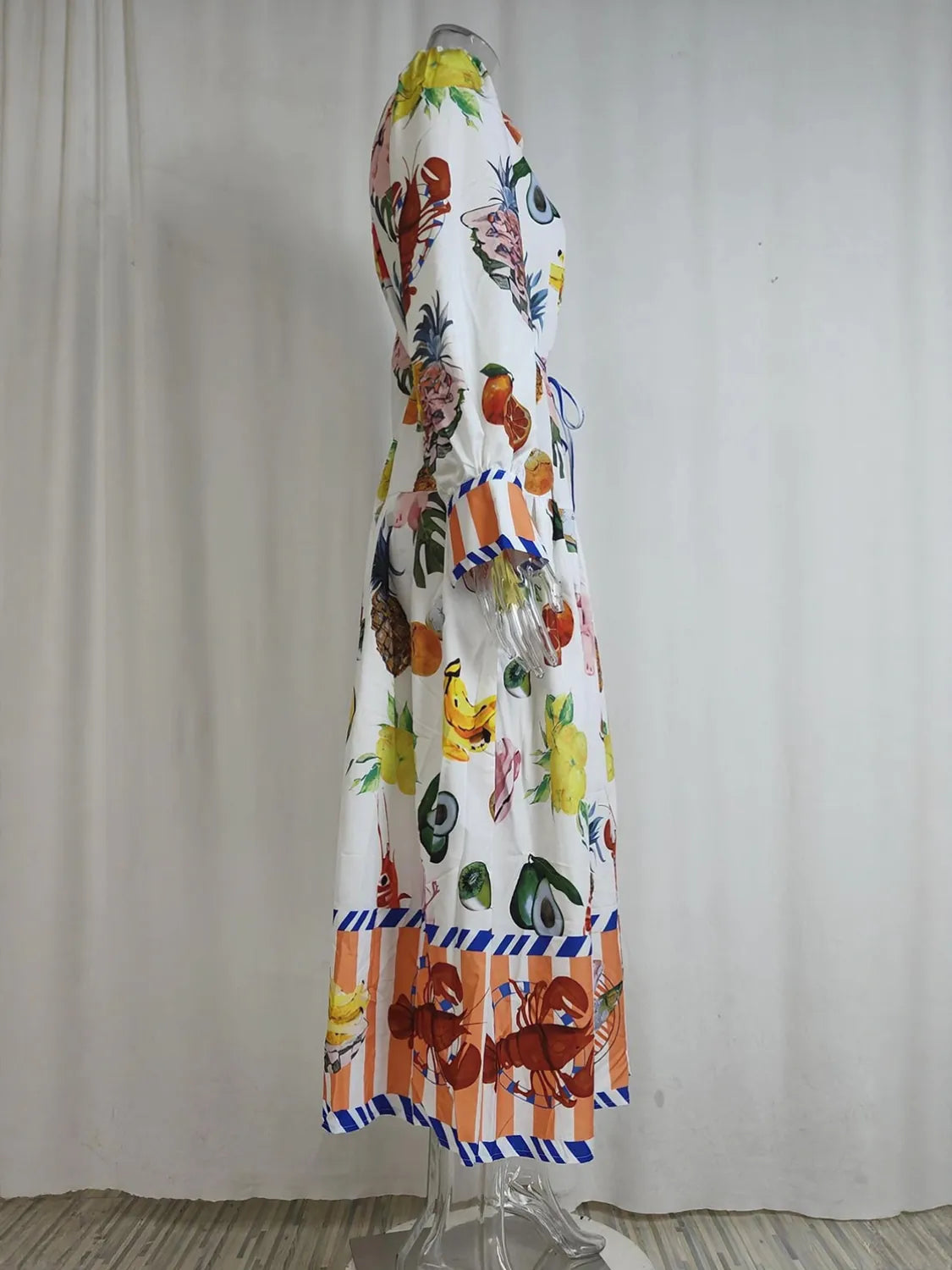 Colorful dress with fruit pattern on a mannequin against a plain background. #Color_White