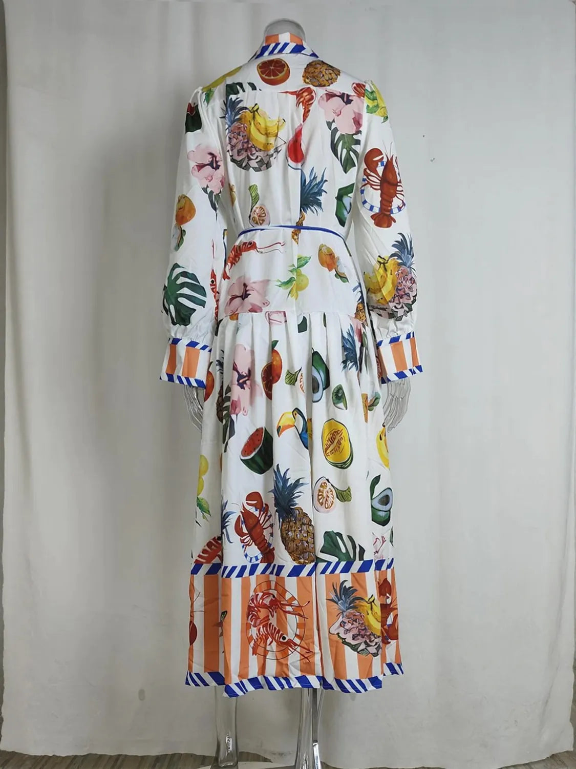 Colorful robe with fruit and floral patterns on a mannequin against a white curtain background. #Color_White