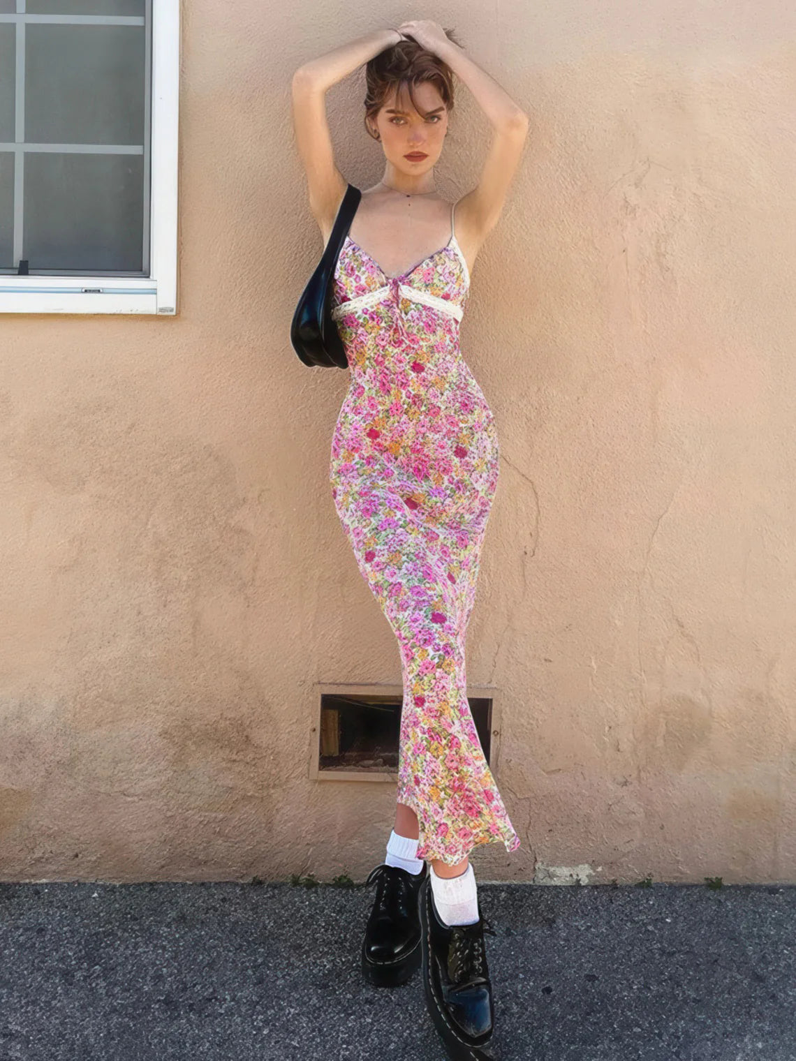 Woman in a floral dress standing against a beige wall | IFAUN.COM