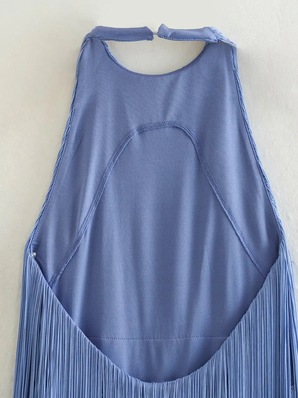 Blue sleeveless top with fringe details on a light beige background. #Color_Blue
