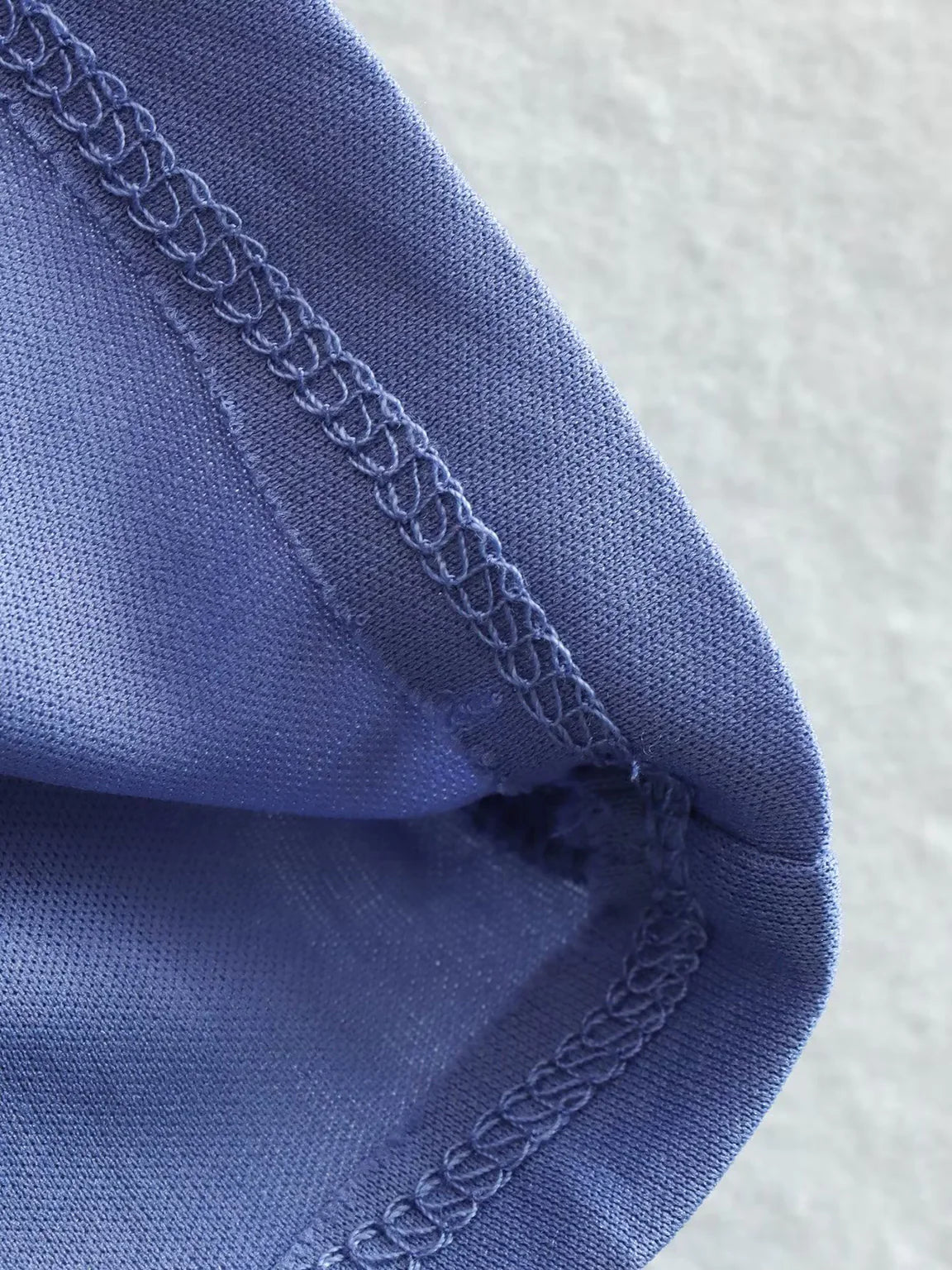 Close-up of blue fabric with intricate stitching on a textured white background. #Addtl