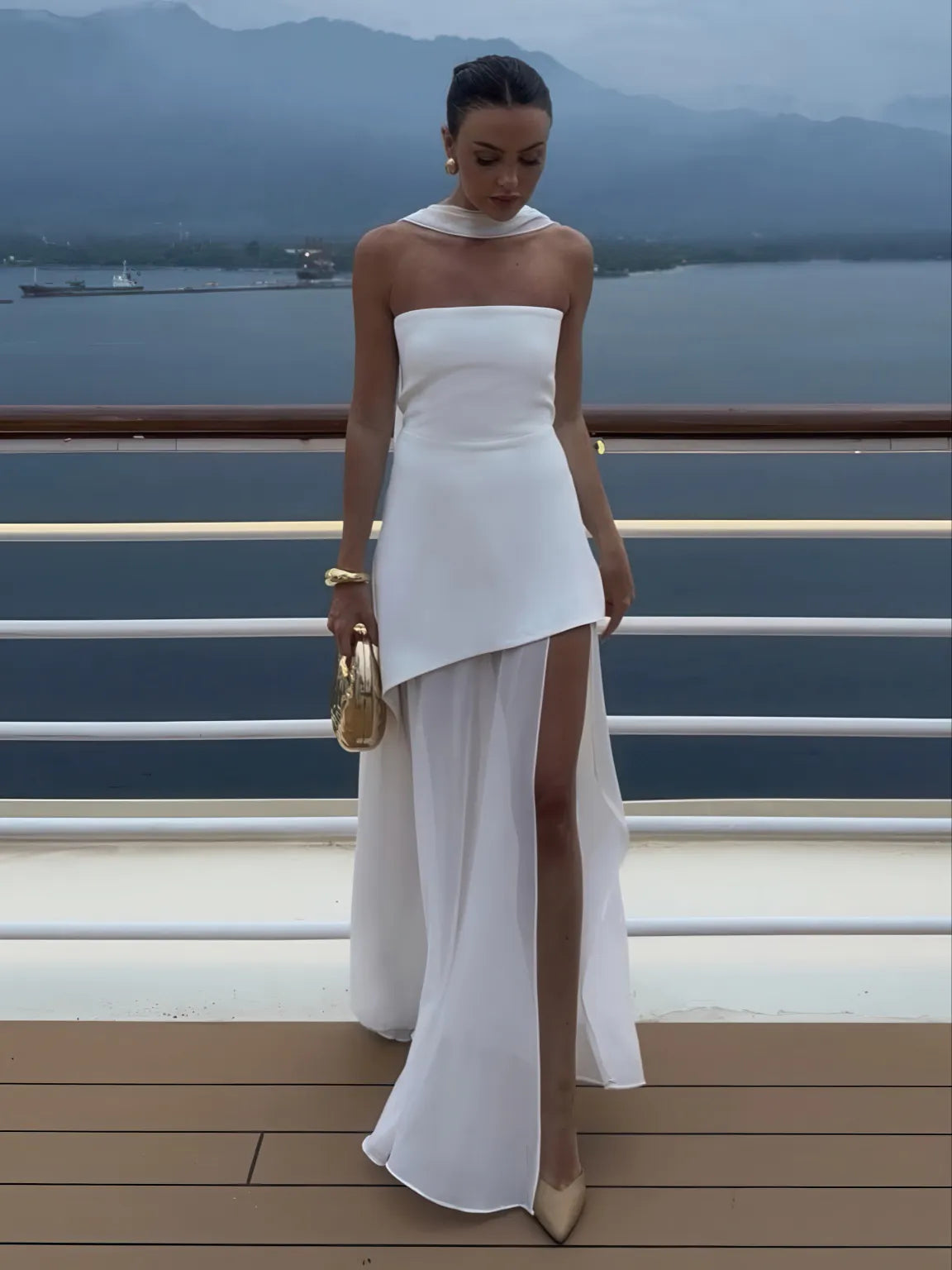 Woman in a white dress standing on a deck with a scenic background. #Color_White