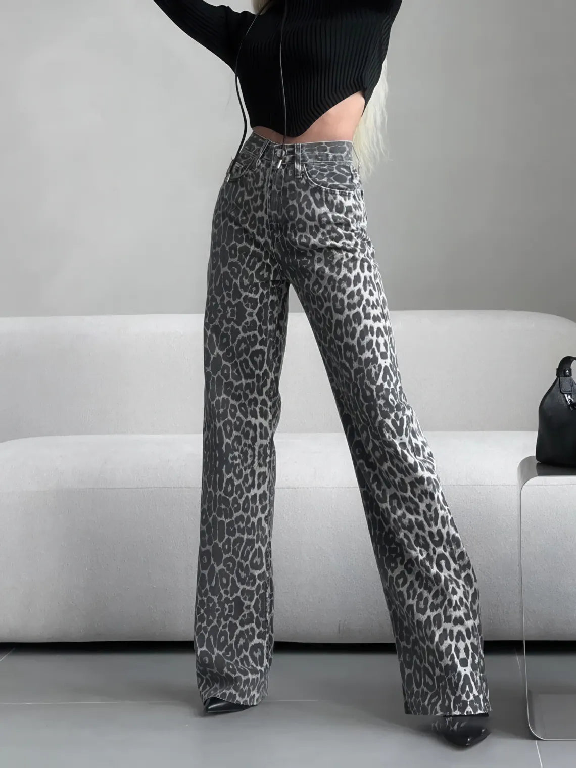Person wearing leopard print pants sitting on a gray couch. #Color_Gray