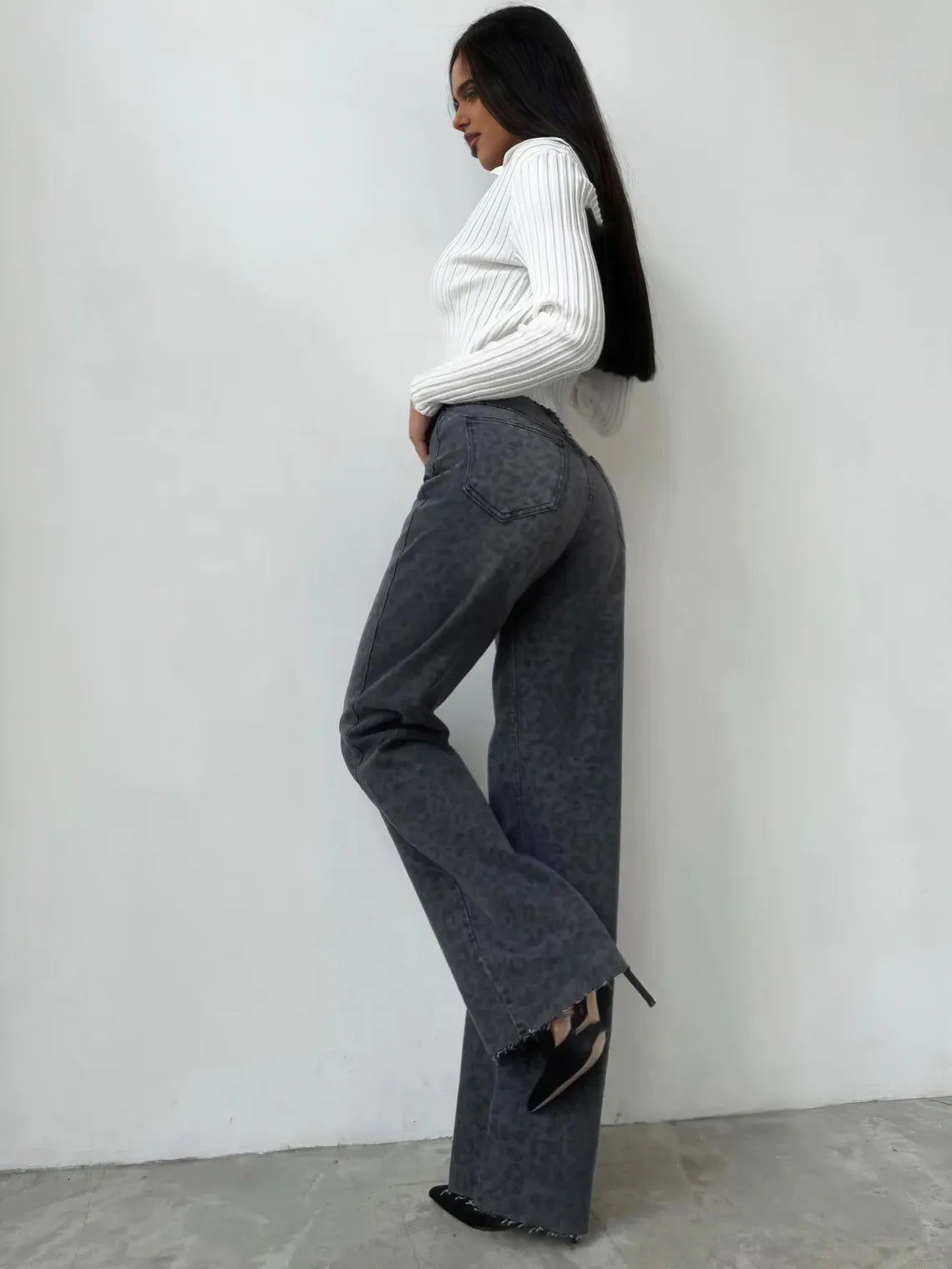 Person wearing a white sweater and gray pants against a plain background. #Color_DimGray