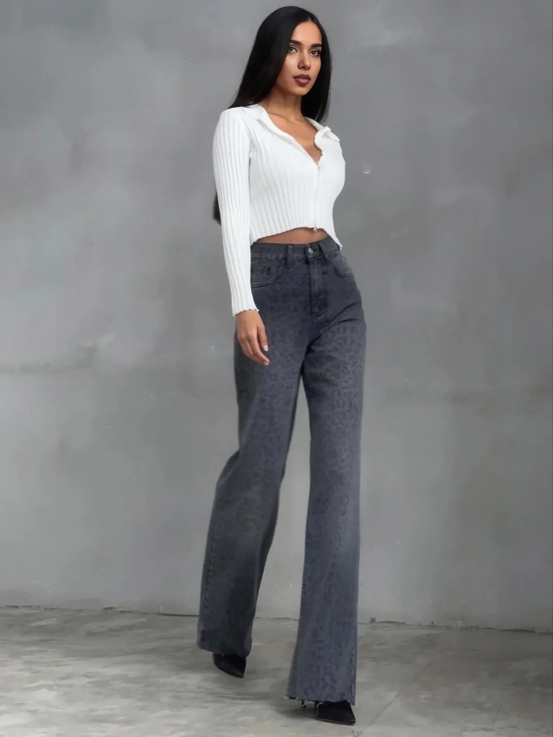 Woman wearing a white ribbed sweater and dark jeans against a gray background. #Color_DimGray