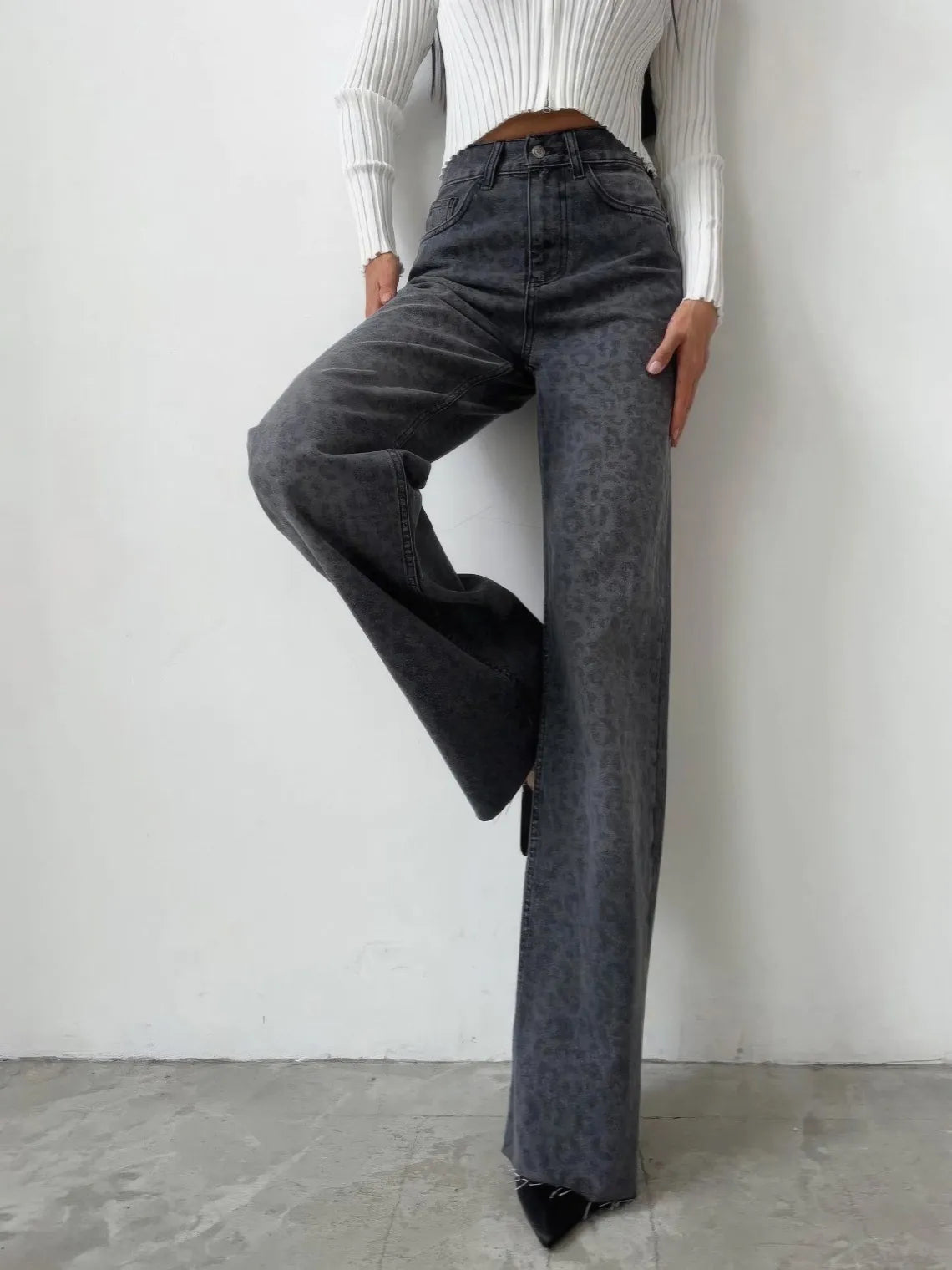 Person wearing high-waisted dark jeans and a white ribbed top against a plain background. #Color_DimGray