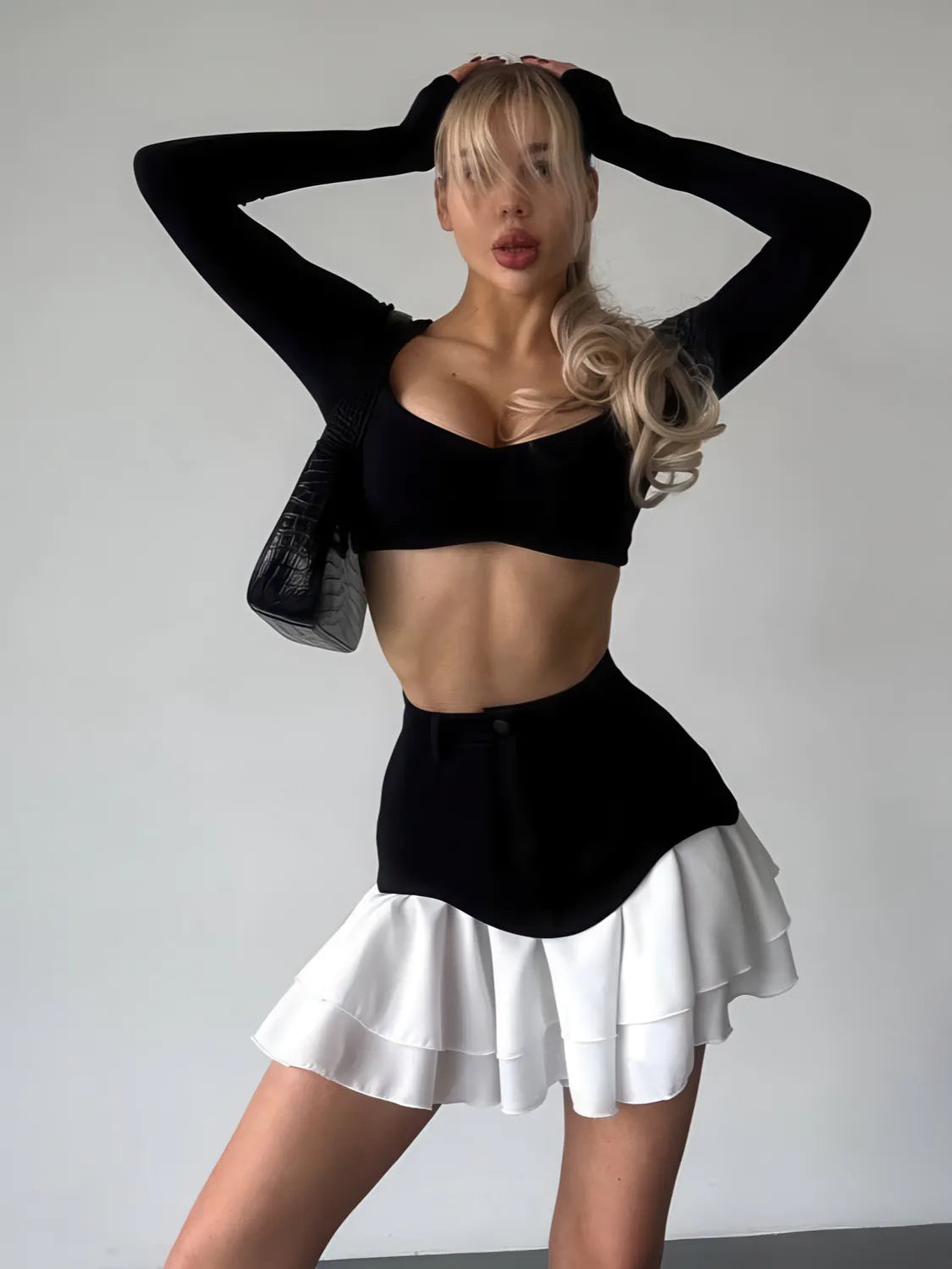 Person wearing a black top and white skirt against a plain background. #Color_Black