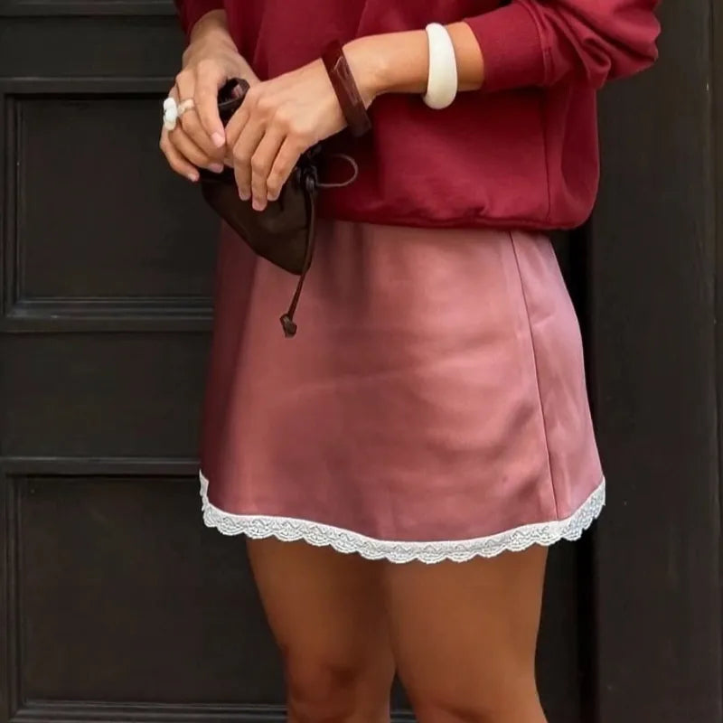 Person wearing a red sweater and red skirt with lace trim against a dark background. #Color_Red