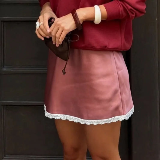 Person wearing a red sweater and red skirt with lace trim against a dark background. #Color_Red