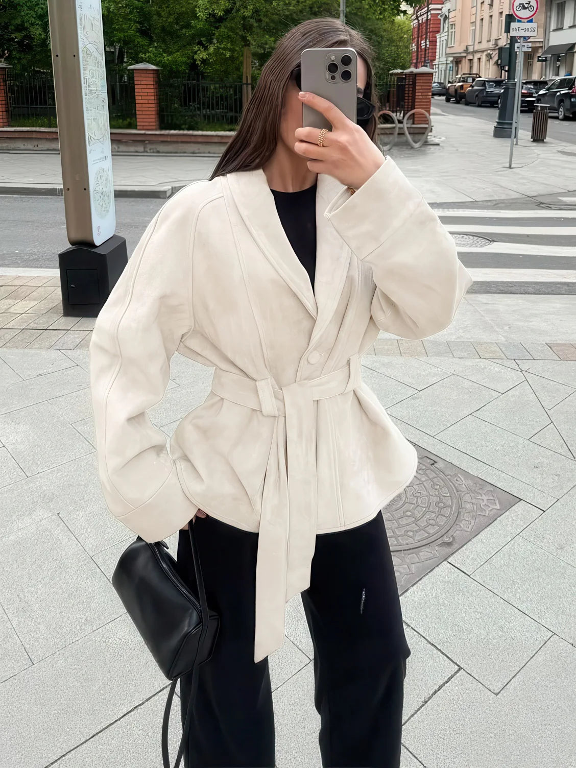 Person wearing a white peplum jacket on a city street. #Color_Beige
